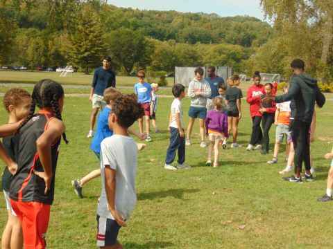 Ayotunde Ejiko and Cornell athletes leading an outdoor activity with children